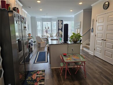 Kitchen with appliances with stainless steel finishes, a sink, crown molding, white cabinetry, and dark wood finished floors
