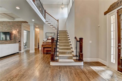 Entryway with wood finished floors, stairs, crown molding, a high ceiling, and recessed lighting