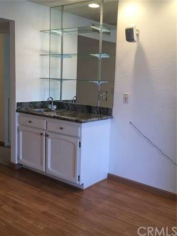wet bar in living room with mirrored shelves