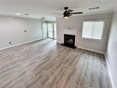 Unfurnished living room featuring crown molding, ceiling fan, wood finished floors, and a fireplace with raised hearth