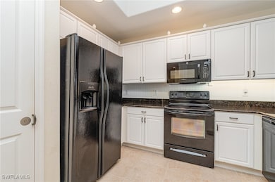 Kitchen featuring dark stone counters, white cabin