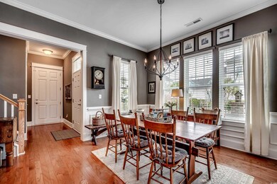 Dining space featuring a chandelier, wood finished floors, visible vents, and crown molding