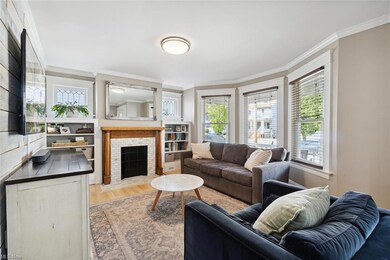 Spacious living room showcases a beautifully restored fireplace, leaded glass windows and striking wood feature wall.