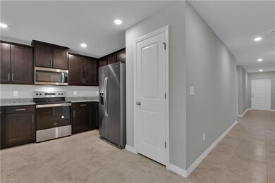 Kitchen featuring stainless steel appliances, dark brown cabinetry, light stone countertops, recessed lighting, and baseboards