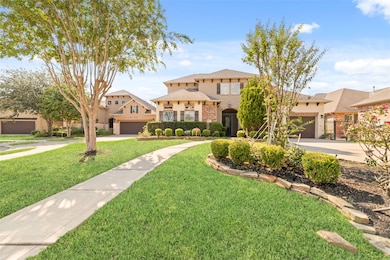 A beautiful two-story home with a well-maintained front yard, featuring manicured bushes and trees. A curved pathway leads to the entrance, and the house has a brick facade with large windows.