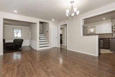 Unfurnished living room featuring a chandelier, stairway, dark wood finished floors, and recessed lighting