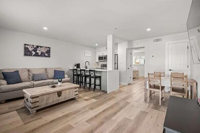 Living area with visible vents, light wood-style 