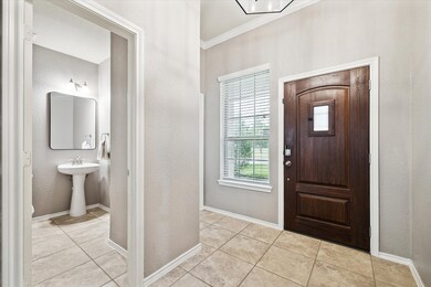 The Entry Showcases a Wood Front Door w/ Speakeasy, Tile Floors, and Crown Molding. Notice the the Nearby Half Bath.