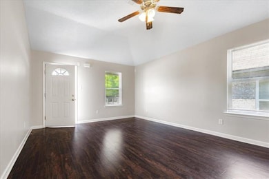 Empty room featuring dark wood-style floors, ceiling fan, and lofted ceiling