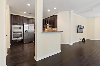 Kitchen with appliances with stainless steel finishes, dark brown cabinets, dark wood-style floors, recessed lighting, and backsplash