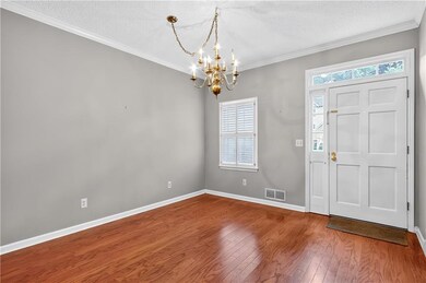 Entryway with a chandelier, wood finished floors, a textured ceiling, and crown molding