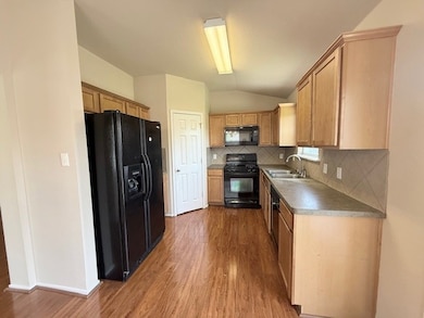 Kitchen featuring black appliances, lofted ceiling