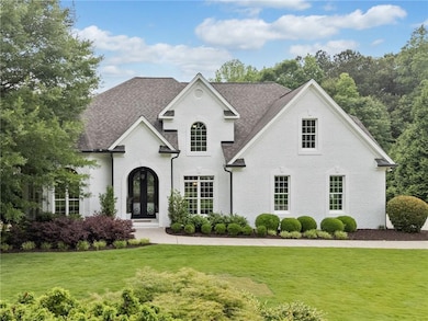 French country inspired facade featuring french doors, brick siding, and a front yard