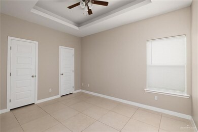 Unfurnished room with baseboards, a ceiling fan, light tile patterned floors, and a tray ceiling