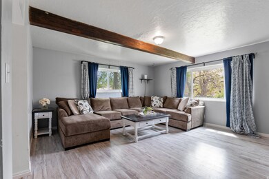 Living room with beam ceiling, light wood-style floors, and a textured ceiling