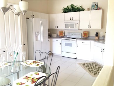 Kitchen with white appliances, light tile patterne