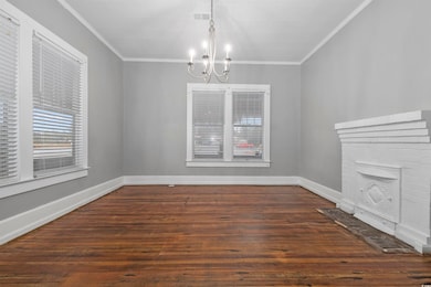 Unfurnished dining area featuring dark hardwood / wood-style floors, crown molding, and a chandelier