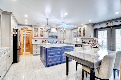 Kitchen with blue cabinets, ornamental molding, tasteful backsplash, recessed lighting, and custom range hood
