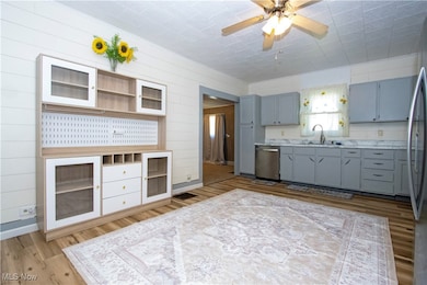 Kitchen featuring gray cabinetry, light countertops, stainless steel appliances, open shelves, and ceiling fan