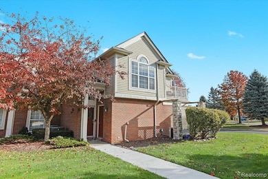 View of front of house featuring a front yard, brick siding, and a balcony
