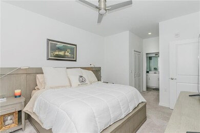 Bedroom featuring light carpet, ensuite bath, and a ceiling fan