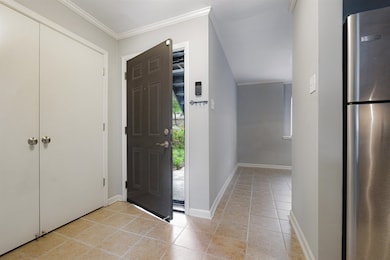 Foyer with crown molding, baseboards, and light ti