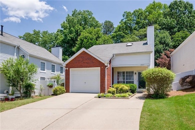 View of front of home with brick siding, a garage, driveway, a front lawn, and a chimney