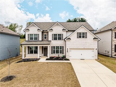 Traditional-style home with concrete driveway, a front yard, covered porch, brick siding, and a garage