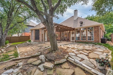 Back of house featuring a pergola, brick siding, a patio area, a chimney, and roof with shingles