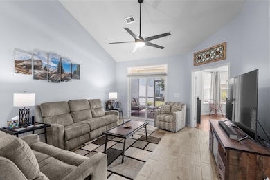 Living room featuring high vaulted ceiling, ceiling fan, and light wood-type flooring