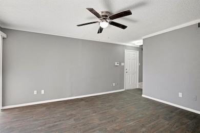Unfurnished room featuring dark wood-type flooring, a textured ceiling, and ceiling fan