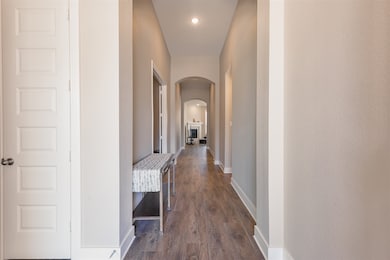 Hall featuring arched walkways, dark wood finished floors, and recessed lighting