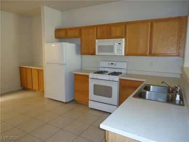 Kitchen with white appliances, light tile patterne