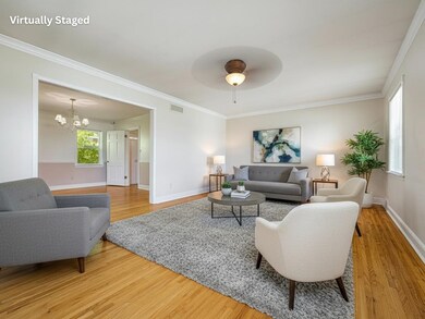 Living area featuring crown molding, light wood finished floors, a chandelier, and a ceiling fan.  Virtually Staged