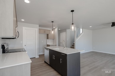 Kitchen featuring hanging light fixtures, light wood-style flooring, appliances with stainless steel finishes, an island with sink, and recessed lighting