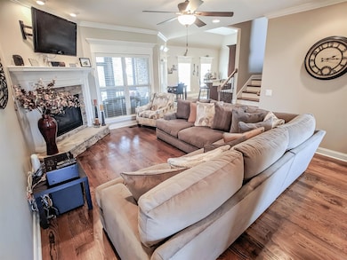 Living room with Extensive Custom Crown moldings and much trim detail over windows and around gas fireplace.