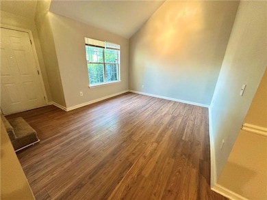 Spare room with vaulted ceiling, wood finished floors, and baseboards