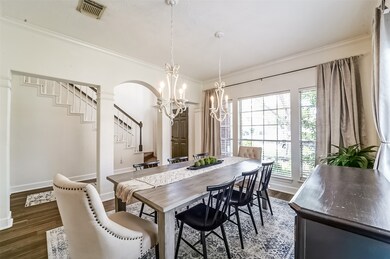 A series of columns, a gracefully arched opening, and ornate crown molding set the stage for this inviting formal dining room anchored by a trio of front-facing windows shaded by 2-inch blinds and beautiful draperies.