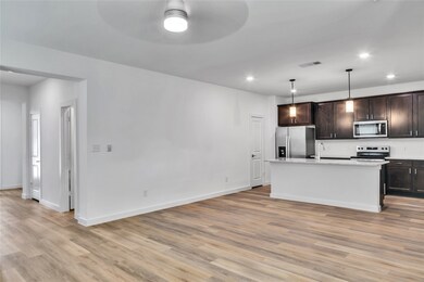 Kitchen featuring dark brown cabinets, appliances with stainless steel finishes, light wood-type flooring, and visible vents