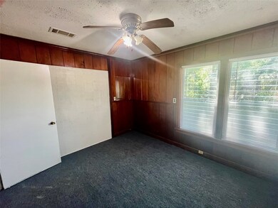 Office, or Spare room featuring a ceiling fan, wood walls, dark carpet, and a textured ceiling