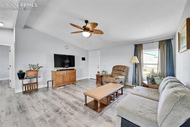 Living area featuring a ceiling fan, lofted ceiling, light wood-style floors, and baseboards