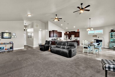 Living area with a chandelier, high vaulted ceiling, a ceiling fan, and light carpet