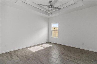 Spare room with baseboards, a ceiling fan, a raised ceiling, and wood finished floors