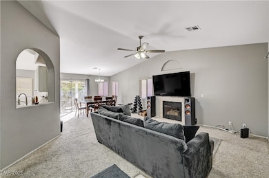 Carpeted living room with lofted ceiling, a tile fireplace, and ceiling fan