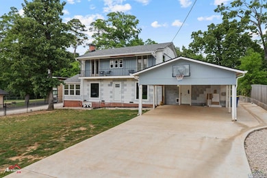 View of front of house featuring a chimney, fence, a balcony, concrete driveway, and a front yard