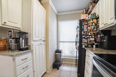Kitchen with crown molding, white cabinetry, ligh