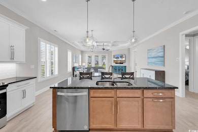 Kitchen with appliances with stainless steel finishes, a sink, light wood-type flooring, an island with sink, and coffered ceiling