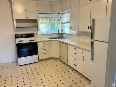 Kitchen with light countertops, white appliances, and light floors