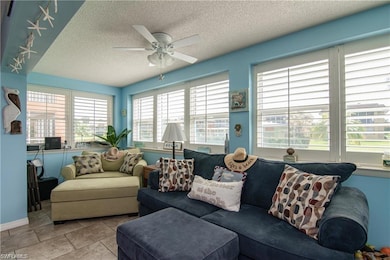 Living room with a textured ceiling, ceiling fan, baseboards, and rail lighting