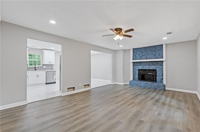 Unfurnished living room featuring a ceiling fan, light wood-style floors, a sink, a fireplace, and recessed lighting
